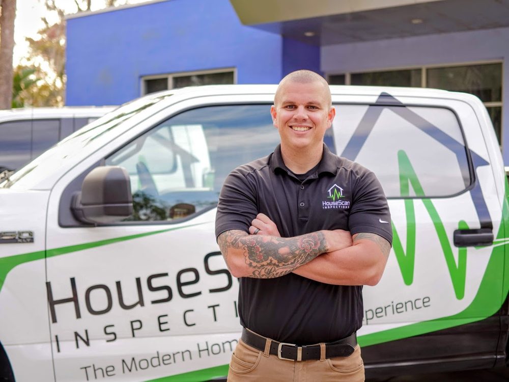 HouseScan inspector standing with arms crossed in front of a branded HouseScan truck