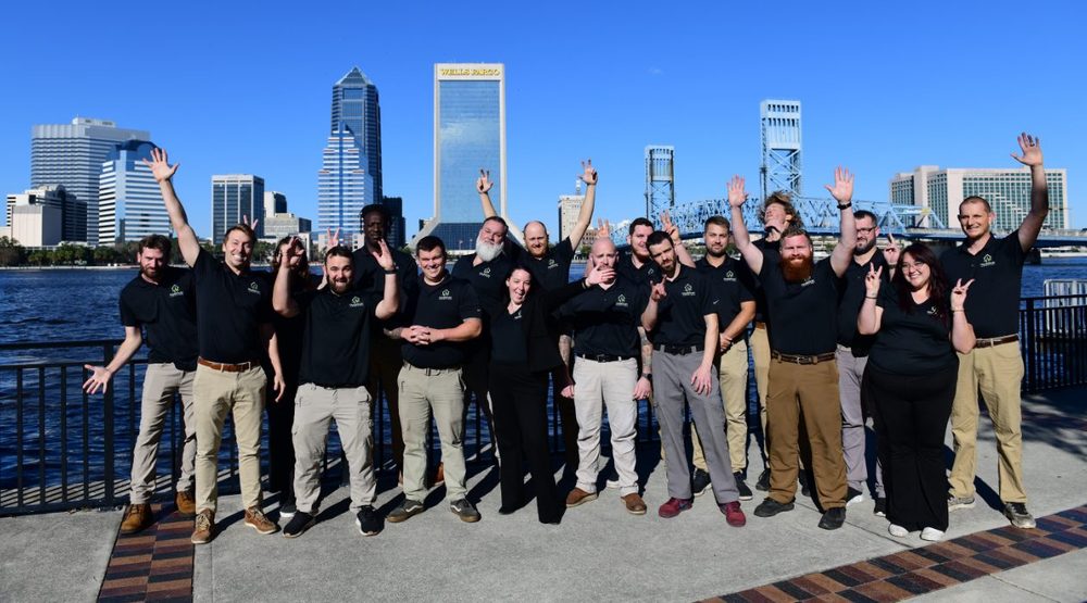 HouseScan Inspections team cheering along the Jacksonville riverfront with the downtown skyline behind them