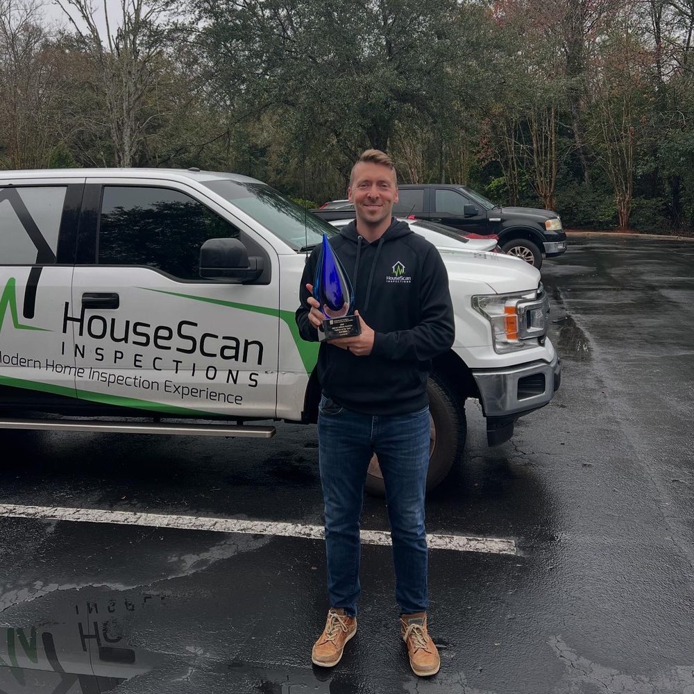 HouseScan team member holding an award in front of a branded HouseScan truck